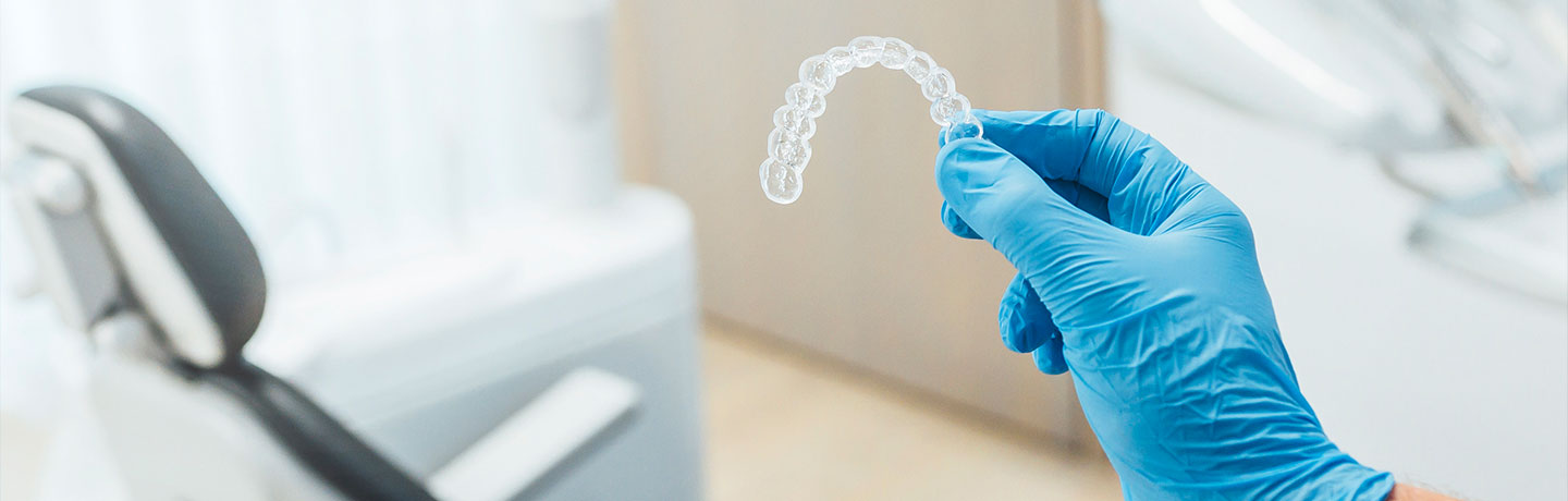 A dentist holding a clear Invisalign in his office