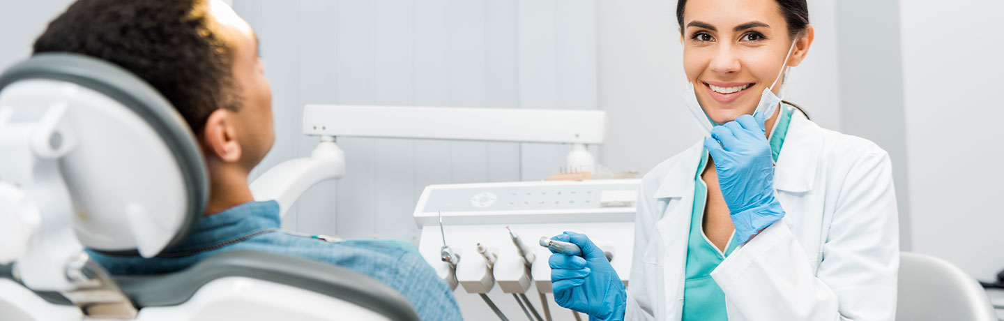 A female dentist looking at the camera, smiling in front a patient during the procedure