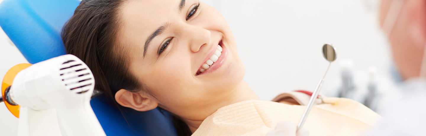 A happy female patient smiling at the camera at the dentist's office